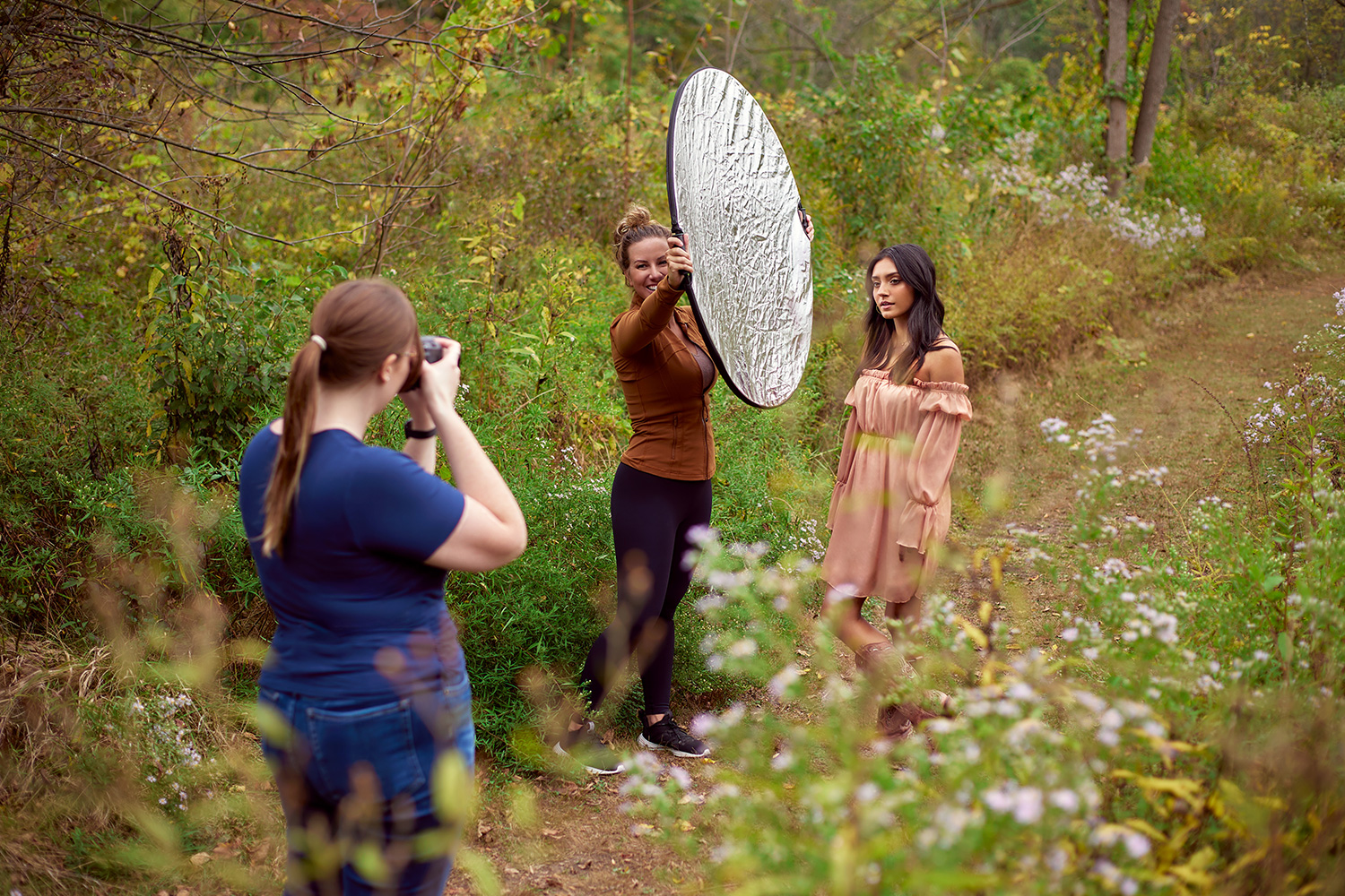 Behind the scenes shot showing a reflector filling in shadows during a natural light portrait.