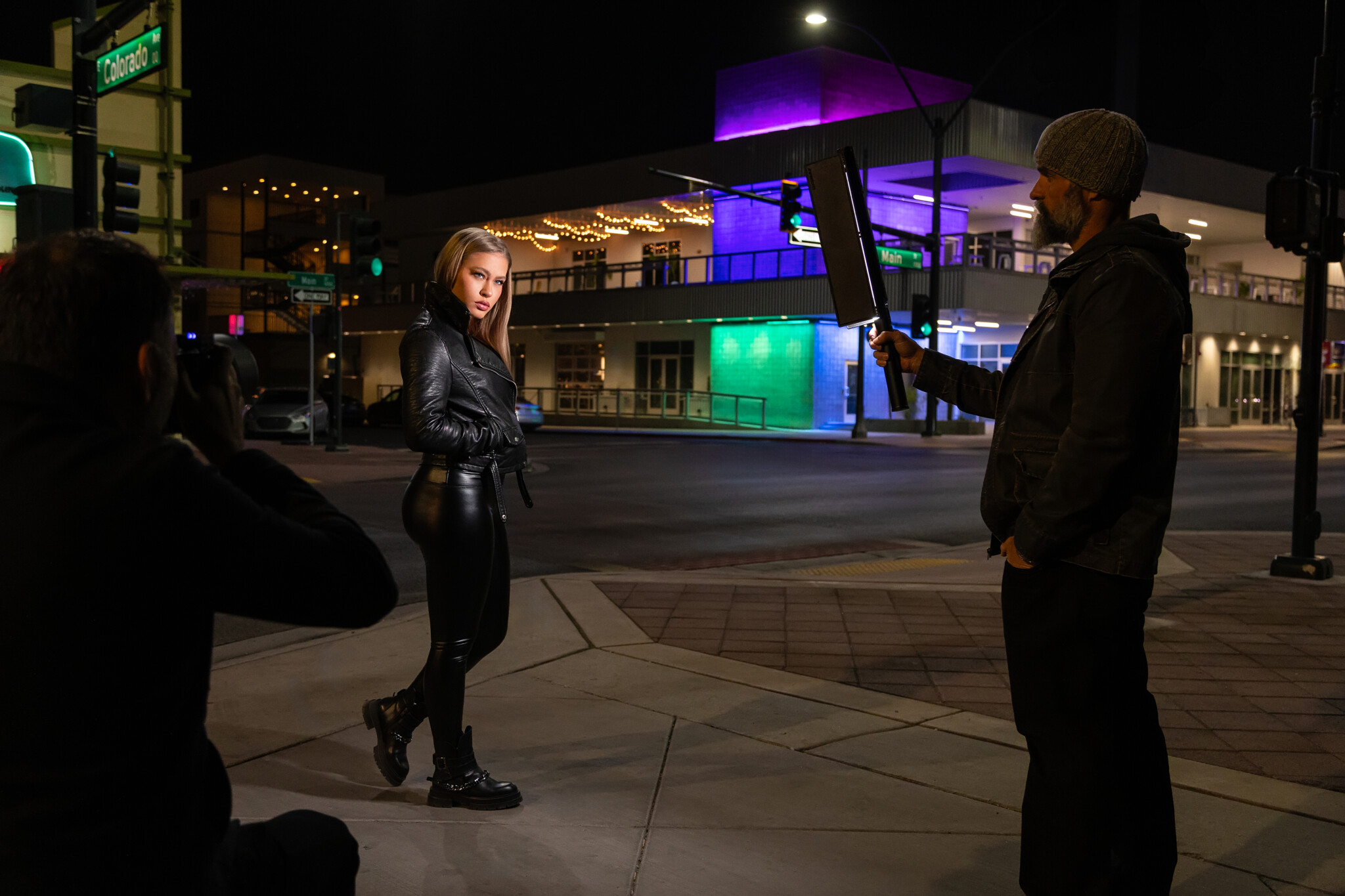 Behind the scenes woman in all black with collar popped