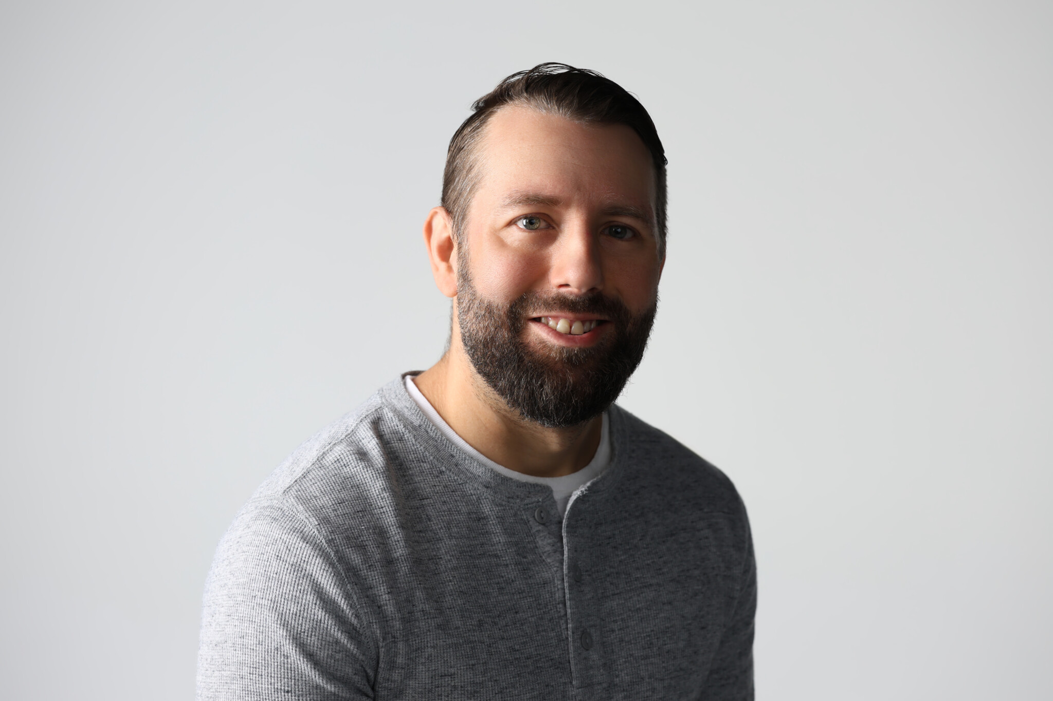 Darker picture with a man with a white background smiling