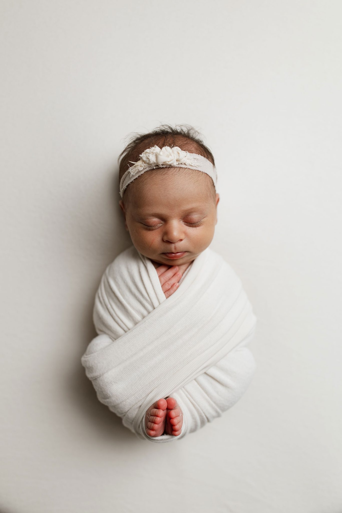 The 7-ft umbrella without diffusion gives a harder light with more shadow detail on the newborn’s features.