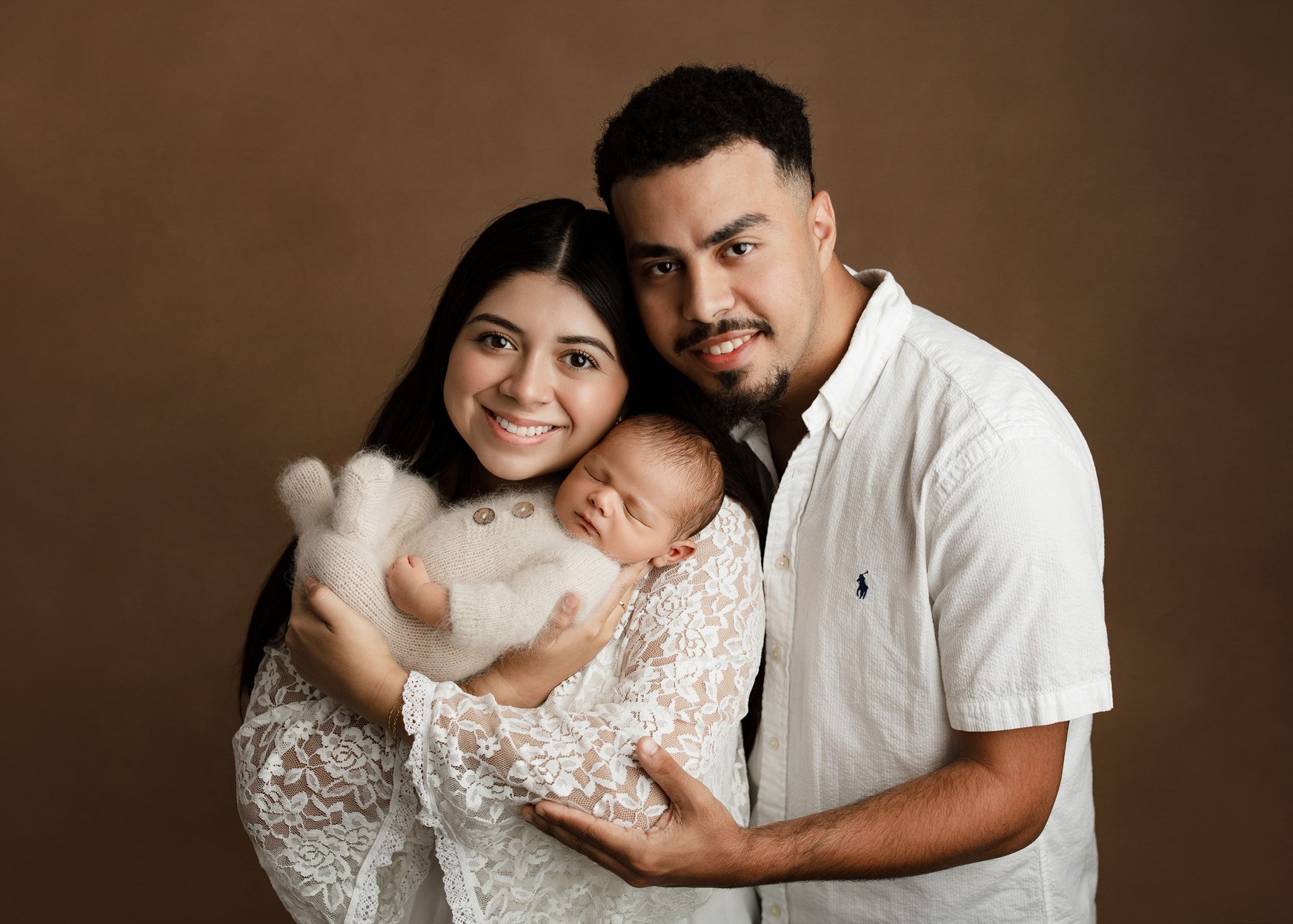 Family portrait lit with the FJ400 II and large umbrella for even light across parents and baby.