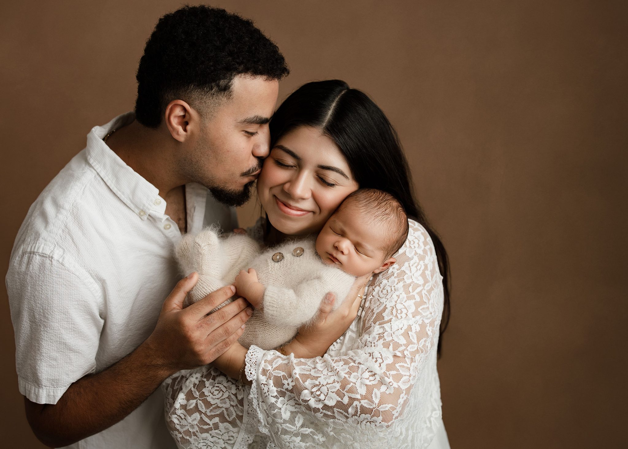 Family Photo Final lit with one FJ400 II and 7-ft umbrella for soft, flattering light across parents and baby.