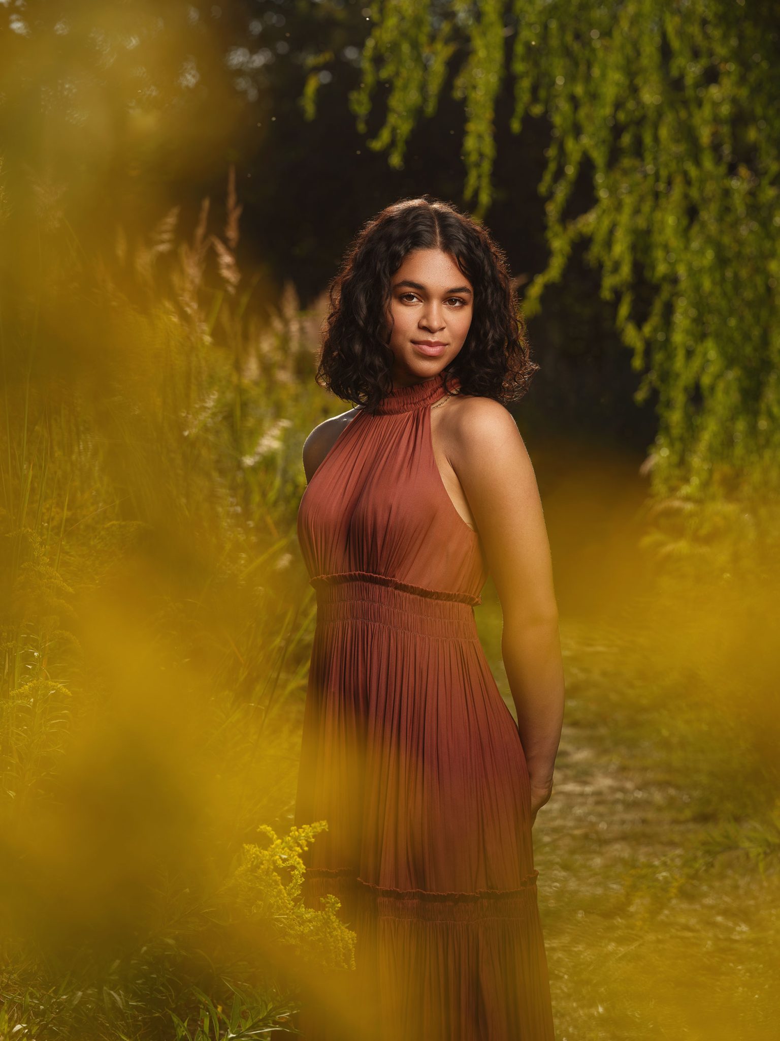 Using foreground flowers and backlit sun to create a dreamy golden hour portrait with layered depth.