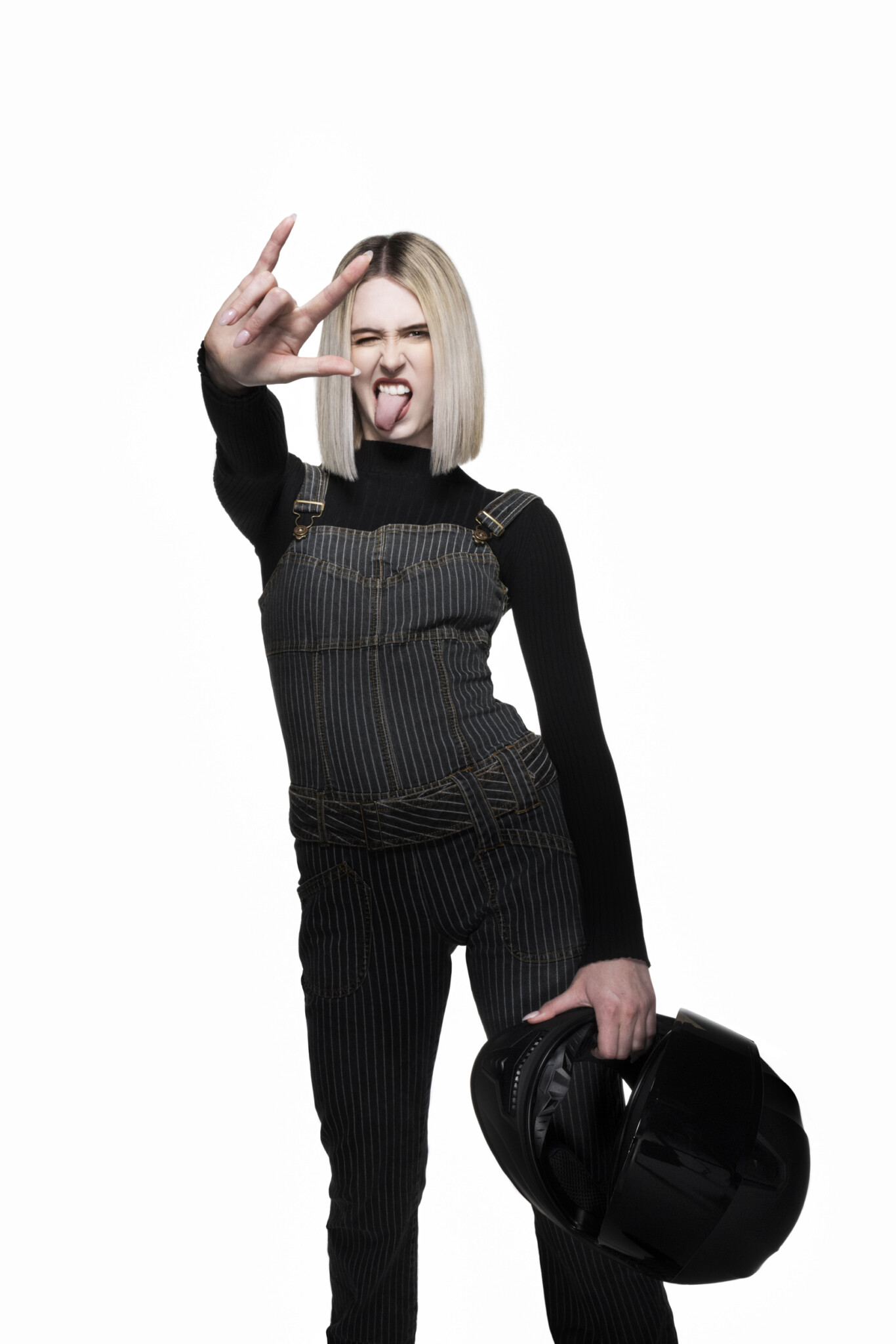 Full-length wide aperture studio portrait of a blonde woman in all black holding a biker helmet with white background