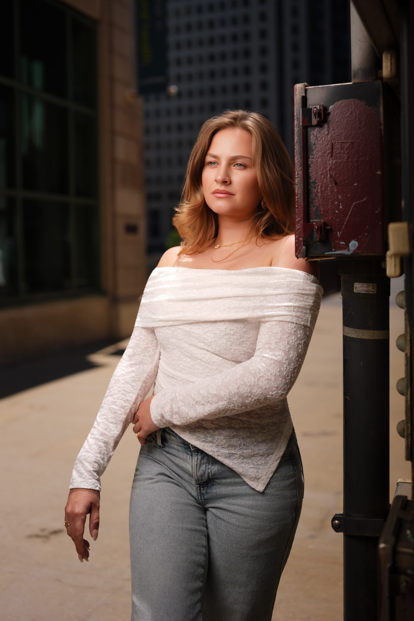 Subject leaning on a street pole creates a relaxed, natural pose.