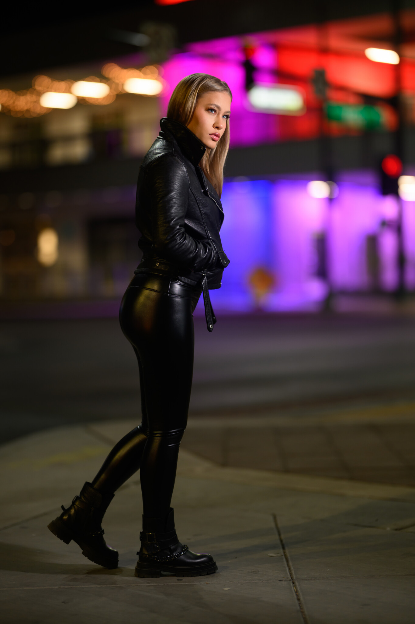 A blond haired woman in a black outfit crossing the street